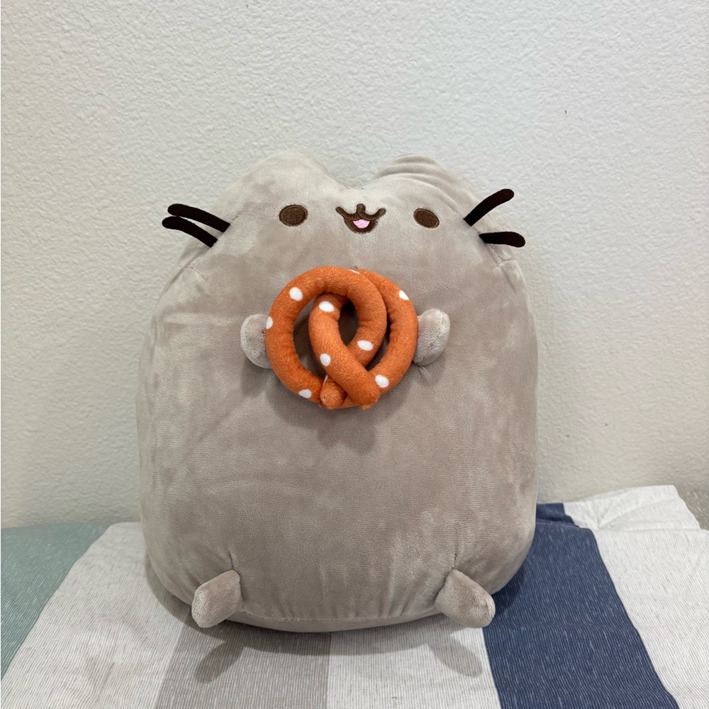 Pusheen the Cat plushie holding a pretzel